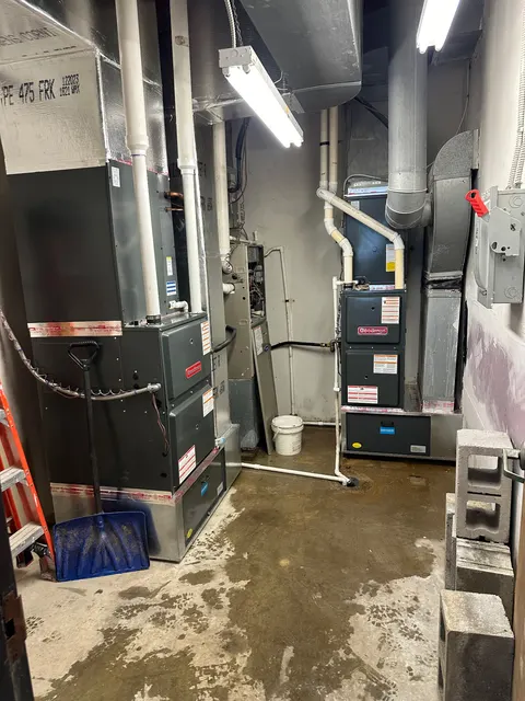 Two Goodman furnace systems with ductwork and white vent piping in a mechanical room.