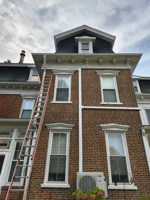 Outdoor ductless mini-split unit beside a brick home, with exterior line-set covers.
