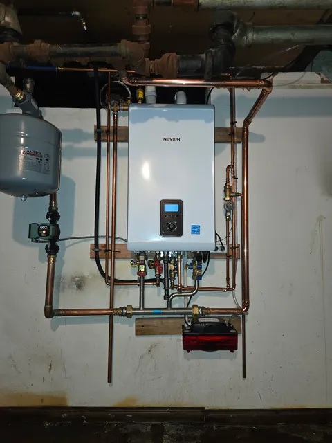 Wall-mounted Navien boiler with copper pipework, a circulation pump and an expansion tank.