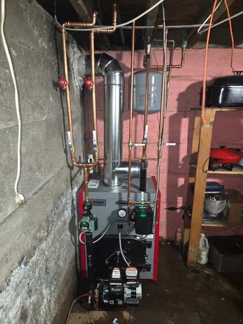 Oil-fired boiler with a front-mounted burner, copper heating pipework and metal flue.